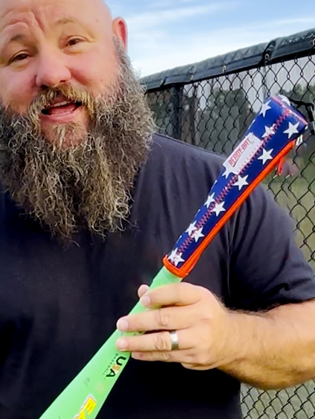 The Dancing Umpire holding a bat with an All Stars Ready Bat cover